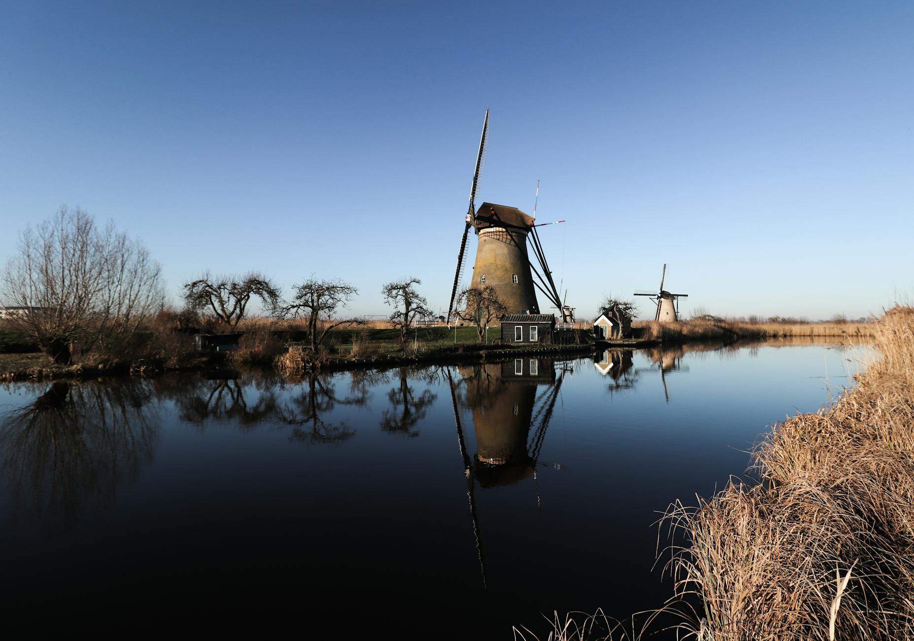Historyczne wiatraki Kinderdijk odbijające się w spokojnej rzece
