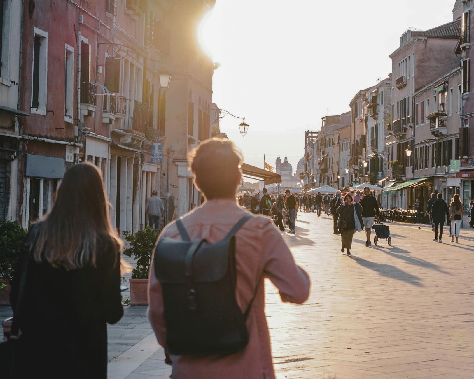 Turyści spacerujący wąską uliczką miasta o zachodzie słońca