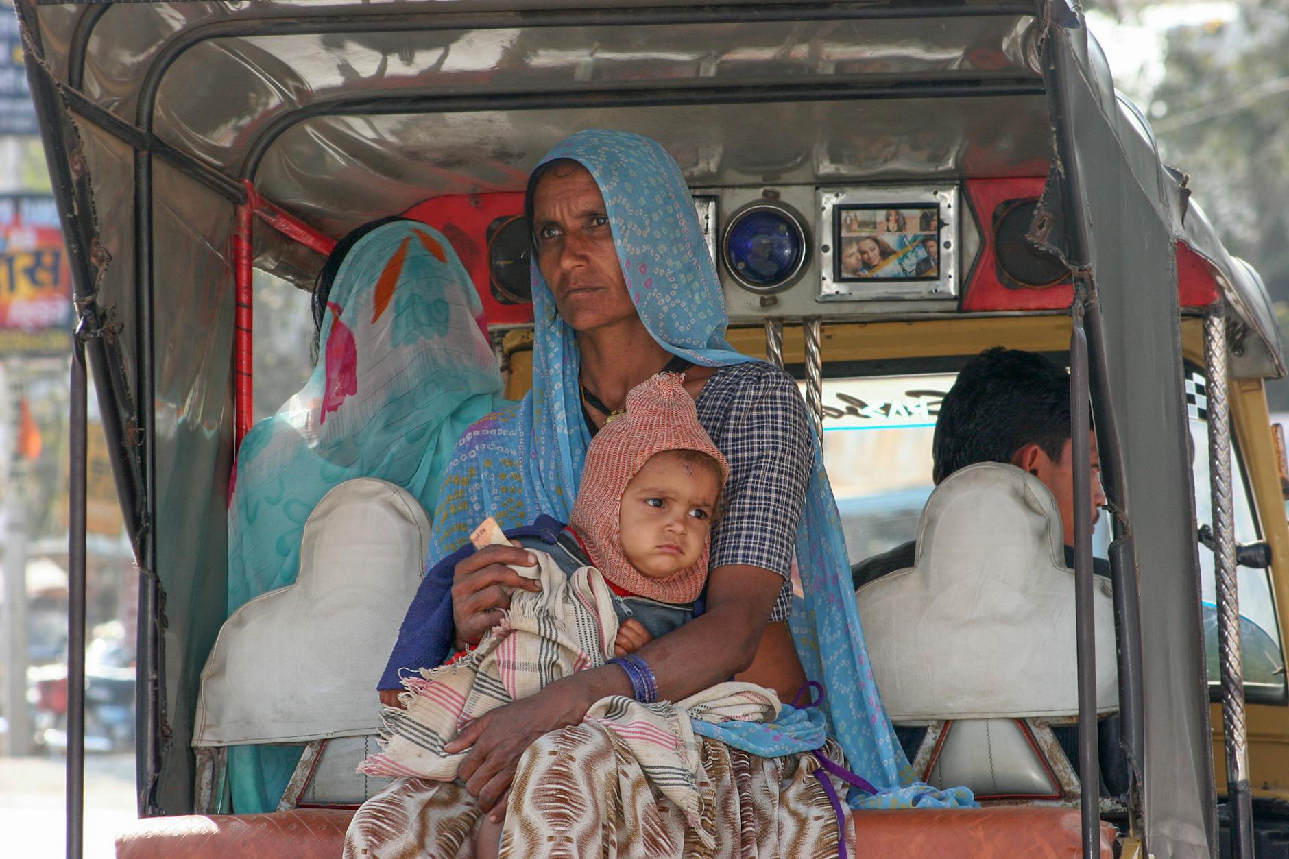 Mama z dzieckiem w tradycyjnych strojach siedząca w indyjskim autobusie