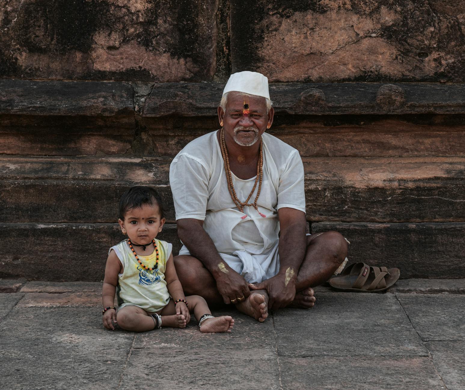 Starszy mężczyzna i dziecko na kamiennych schodach w Ayhole w Indiach